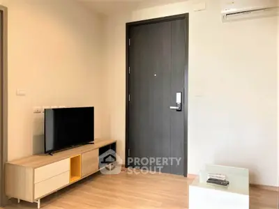 Modern living room with sleek TV stand and air conditioning, featuring a stylish entrance door.