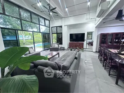 Spacious living room with modern furniture and large windows overlooking a lush garden.