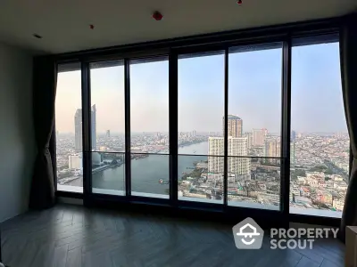 Spacious high-rise corner unit with floor-to-ceiling windows offering panoramic city and river views, bathed in natural light, ideal for luxurious urban living.