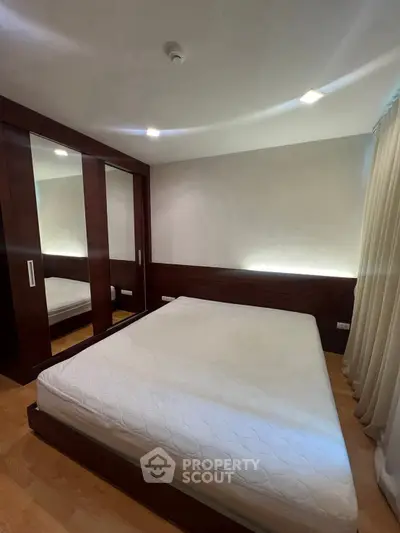 Modern bedroom with wooden accents and large mirrored wardrobe