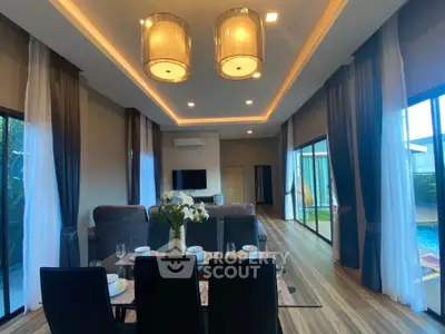 Luxurious open-plan living room with pool view, elegant lighting, and modern decor.