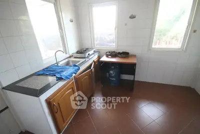 Bright kitchen with tiled walls, wooden cabinets, and gas stove setup.