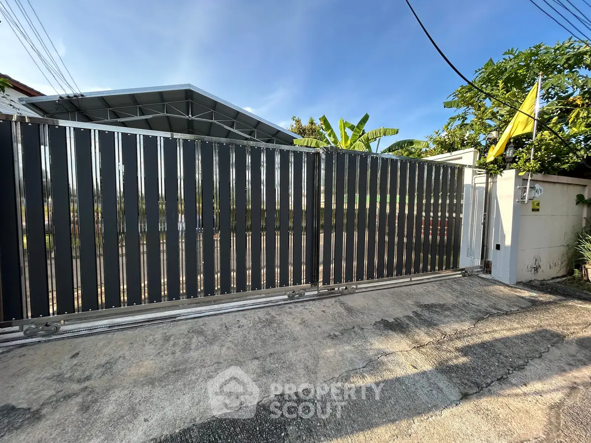 Modern gated entrance with sleek metal design and lush greenery, perfect for secure and stylish living.