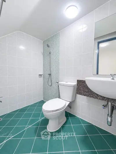 Modern bathroom with green tiled floor and sleek fixtures