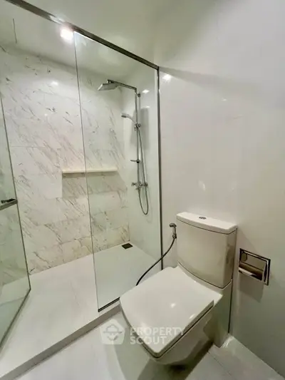 Modern bathroom with glass shower and sleek toilet in luxury apartment