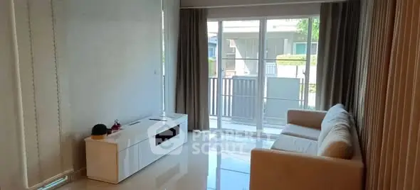 Bright living room with modern sofa and large windows leading to balcony.
