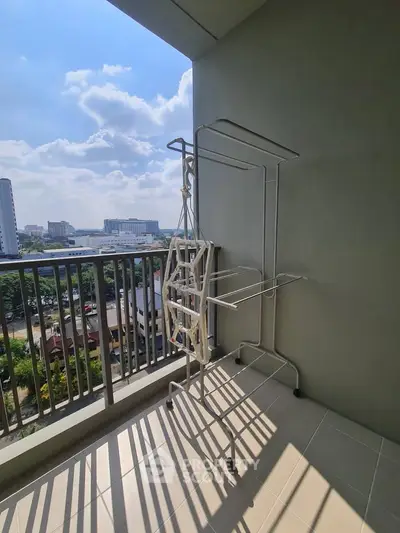 Spacious balcony with city view and laundry rack, perfect for urban living.