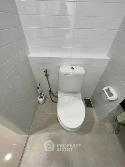 Modern bathroom with sleek white tiles and contemporary toilet design.