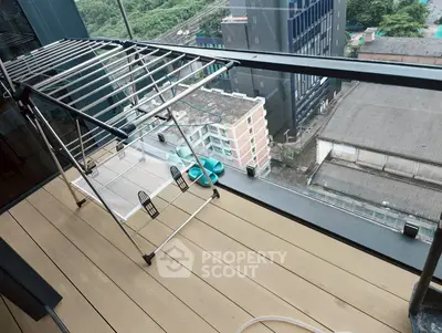 Spacious balcony with city view, featuring a drying rack and modern glass railing.