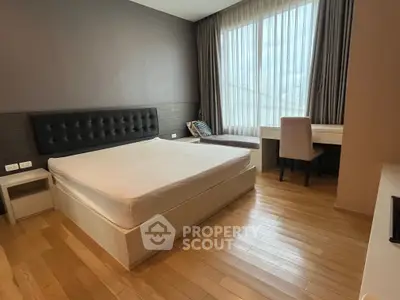 Spacious modern bedroom with large window and wooden flooring