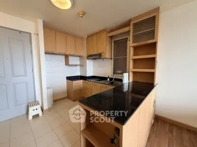 Modern kitchen with sleek black countertops and wooden cabinetry in a cozy apartment.