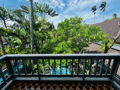Tropical balcony view with lush greenery and clear blue sky, perfect for relaxation.