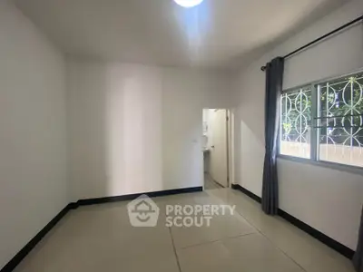 Spacious empty room with tiled floor and window view, ready for customization.