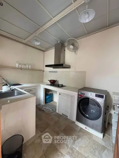 Charming kitchen with modern appliances and open layout, featuring a washing machine and ample counter space.