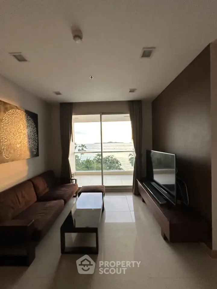 Spacious living room with modern decor and stunning sea view from large windows.