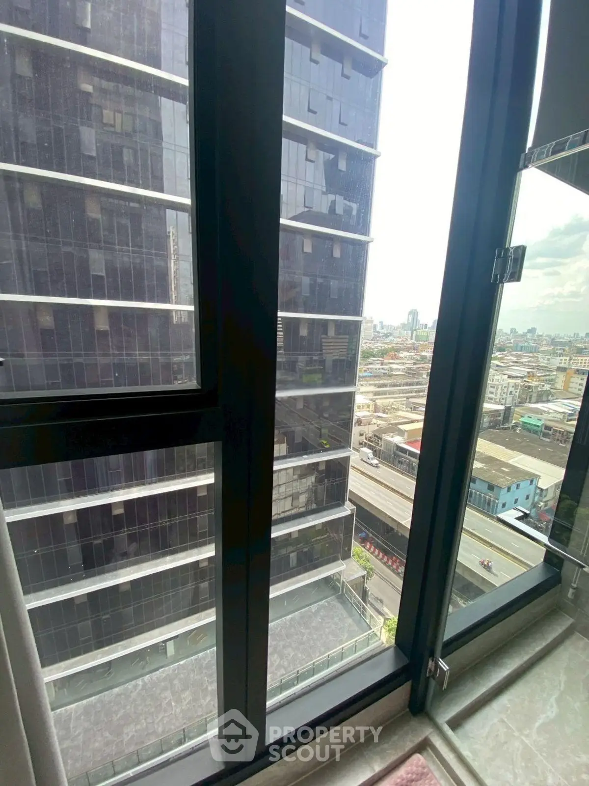 High-rise city view from modern apartment window with urban skyline.