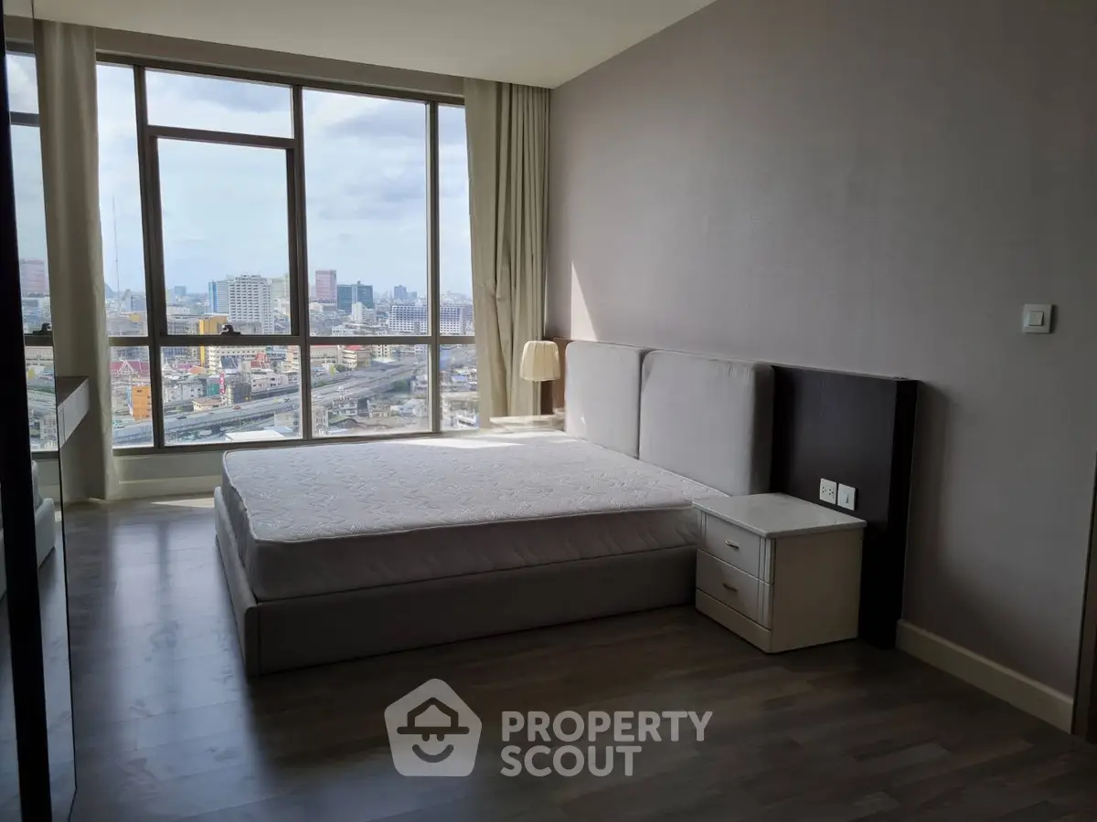 Spacious bedroom with large windows offering stunning city views in a modern apartment.