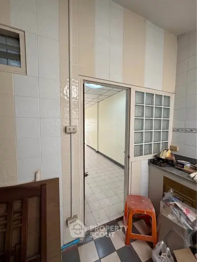 Cozy kitchen space with tiled walls and open doorway leading to a bright hallway.