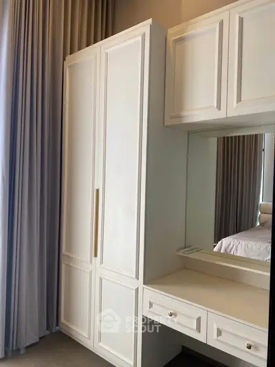 Elegant bedroom with built-in wardrobe and vanity mirror, showcasing modern design and ample storage space.