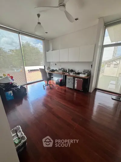 Spacious study room with wooden flooring and large windows for natural light.