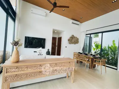 Luxurious open-plan living room with elegant wooden furniture and large windows overlooking lush greenery.