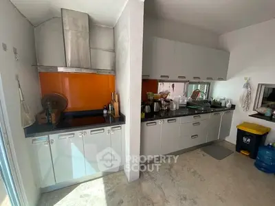 Modern kitchen with sleek cabinetry and vibrant orange backsplash