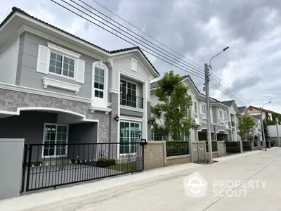 Modern suburban homes with elegant facades and gated driveways on a cloudy day.