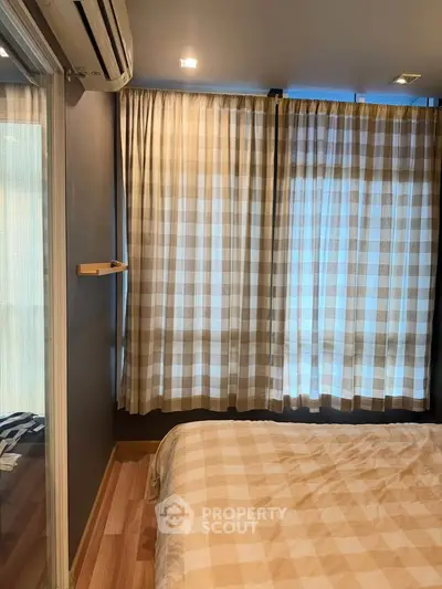 Cozy bedroom with checkered curtains and air conditioning, perfect for relaxation.