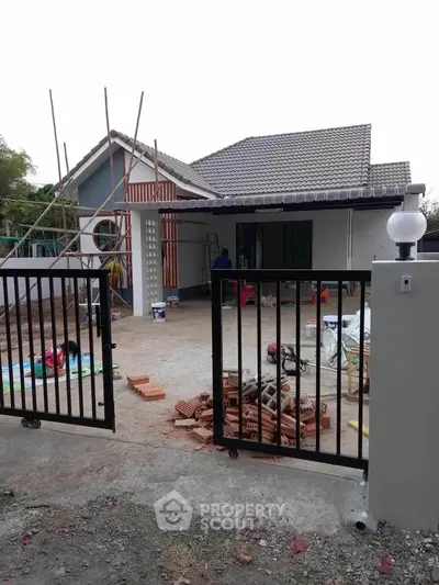 Charming single-story house under renovation with spacious driveway and modern gate.