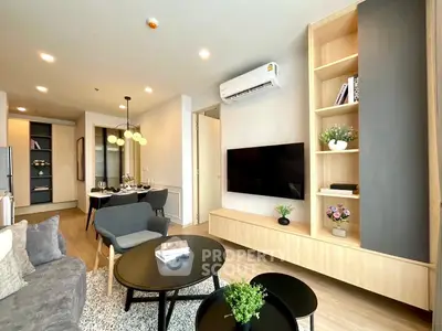 Modern living room with stylish furniture and built-in storage, featuring a sleek TV setup and elegant decor.