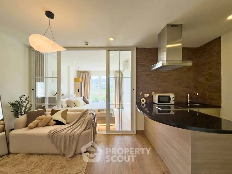 Modern open-layout kitchen and living area with cozy bedroom view