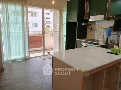 Modern kitchen with green cabinets and balcony view, featuring sleek countertops and ample natural light.