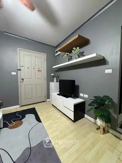 Modern living room with sleek furniture and stylish decor, featuring a TV stand and floating shelves.