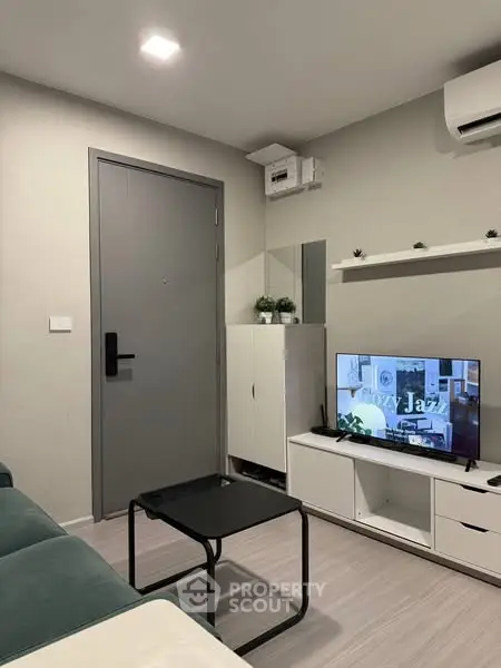 Modern living room with sleek furniture and wall-mounted TV in a cozy apartment.