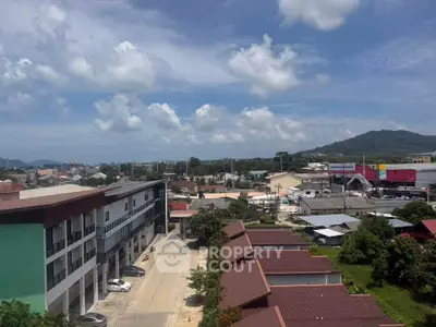 Scenic aerial view of suburban area with commercial buildings and lush greenery under a clear blue sky.