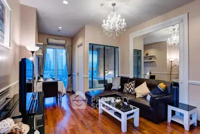Elegant living room with chandelier and city view, featuring modern decor and hardwood floors.