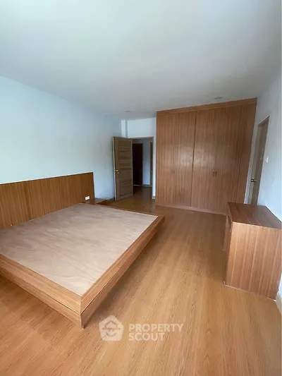 Spacious bedroom with wooden flooring and built-in wardrobe, perfect for modern living.
