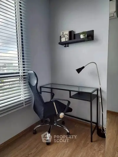 Modern study nook with glass desk, ergonomic chair, and stylish decor in a bright room with city view.