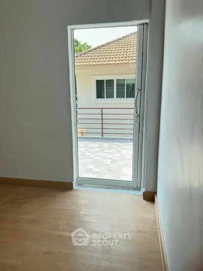 Bright and airy room with wooden flooring leading to a secure gated entrance, offering a blend of comfort and safety in a serene neighborhood.
