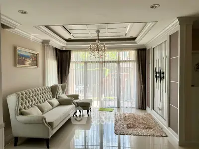 Elegant living room with chandelier and plush seating, featuring large windows and stylish decor.