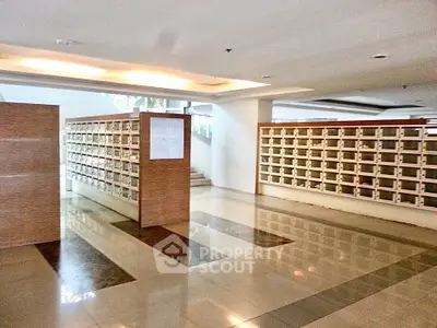Spacious modern lobby with mailboxes in a residential building, featuring sleek design and ample natural light.