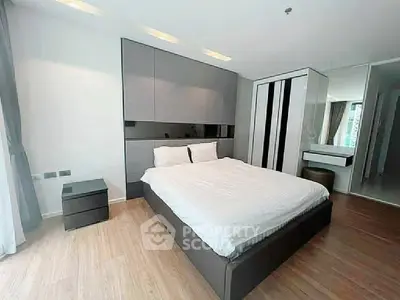 Modern bedroom with sleek design and ample natural light, featuring a stylish bed and contemporary furnishings.