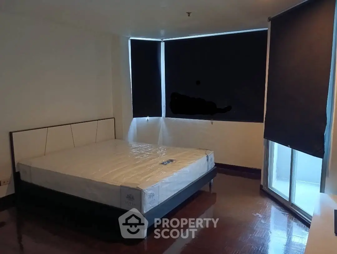 Spacious bedroom with large windows and modern design in a real estate property.