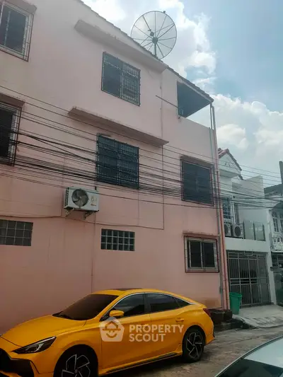 Urban residential building with satellite dish and parked yellow car