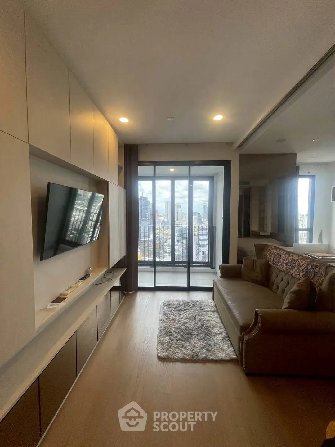Modern living room with city view, sleek TV setup, and cozy sofa.