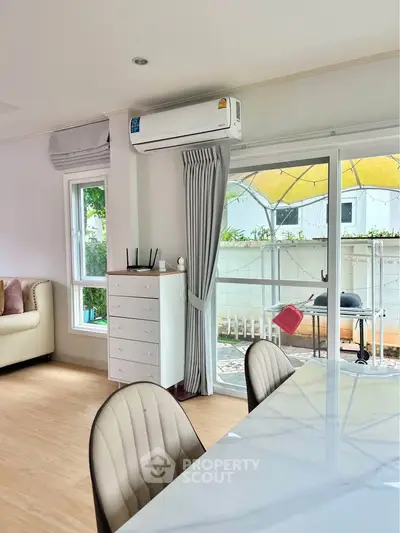 Spacious living room with modern decor and large windows opening to a cozy balcony.