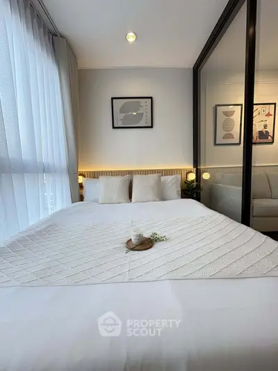 Cozy bedroom with modern decor and large mirror reflecting natural light