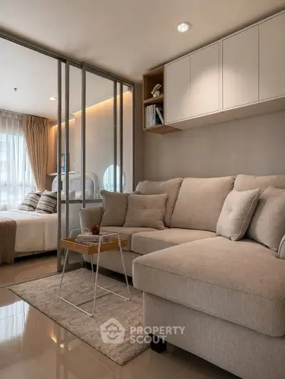 Modern living room with cozy beige sofa and glass partition to bedroom