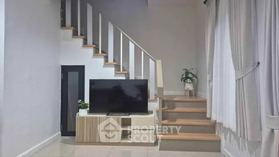 Modern living room with stylish staircase and TV setup