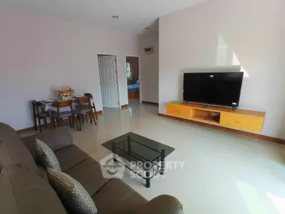 Spacious living room with modern furniture and large TV, perfect for relaxation and entertainment.